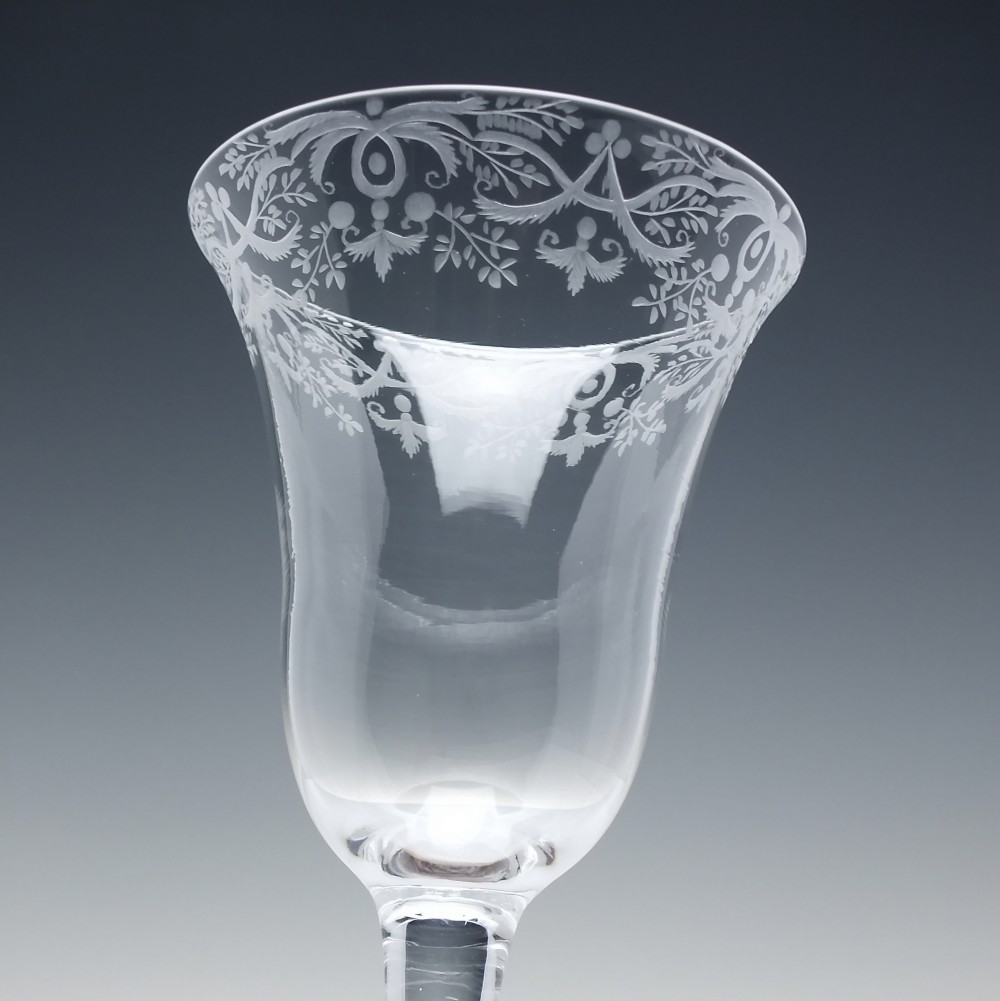 A clear 18th-century lead glass goblet featuring an engraved scroll border along the rim, a plain stem, and a circular foot. View IV