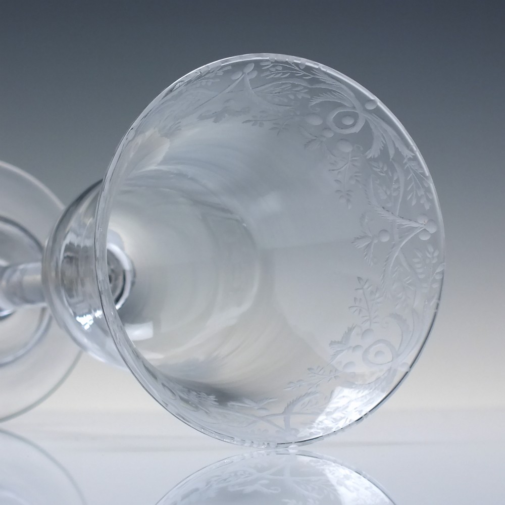 A clear 18th-century lead glass goblet featuring an engraved scroll border along the rim, a plain stem, and a circular foot. View V