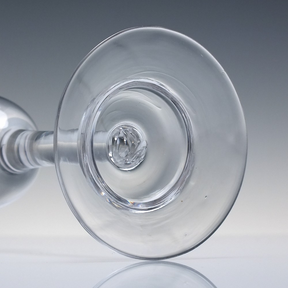 A clear 18th-century lead glass goblet featuring an engraved scroll border along the rim, a plain stem, and a circular foot. View VI