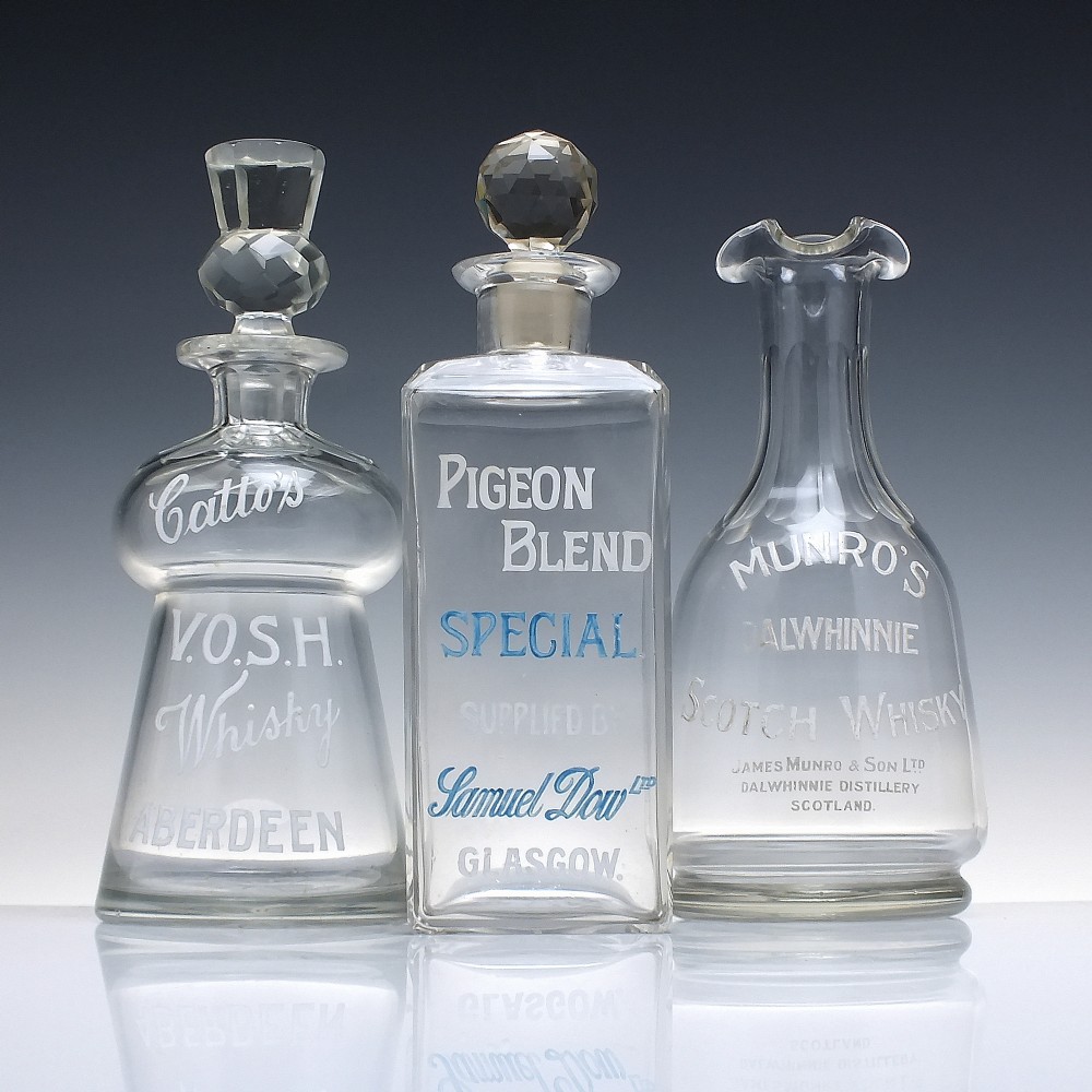 A rectangular clear glass whisky decanter featuring white and blue enamelled text reading Pigeon Blend Special and topped with a faceted glass stopper. View II