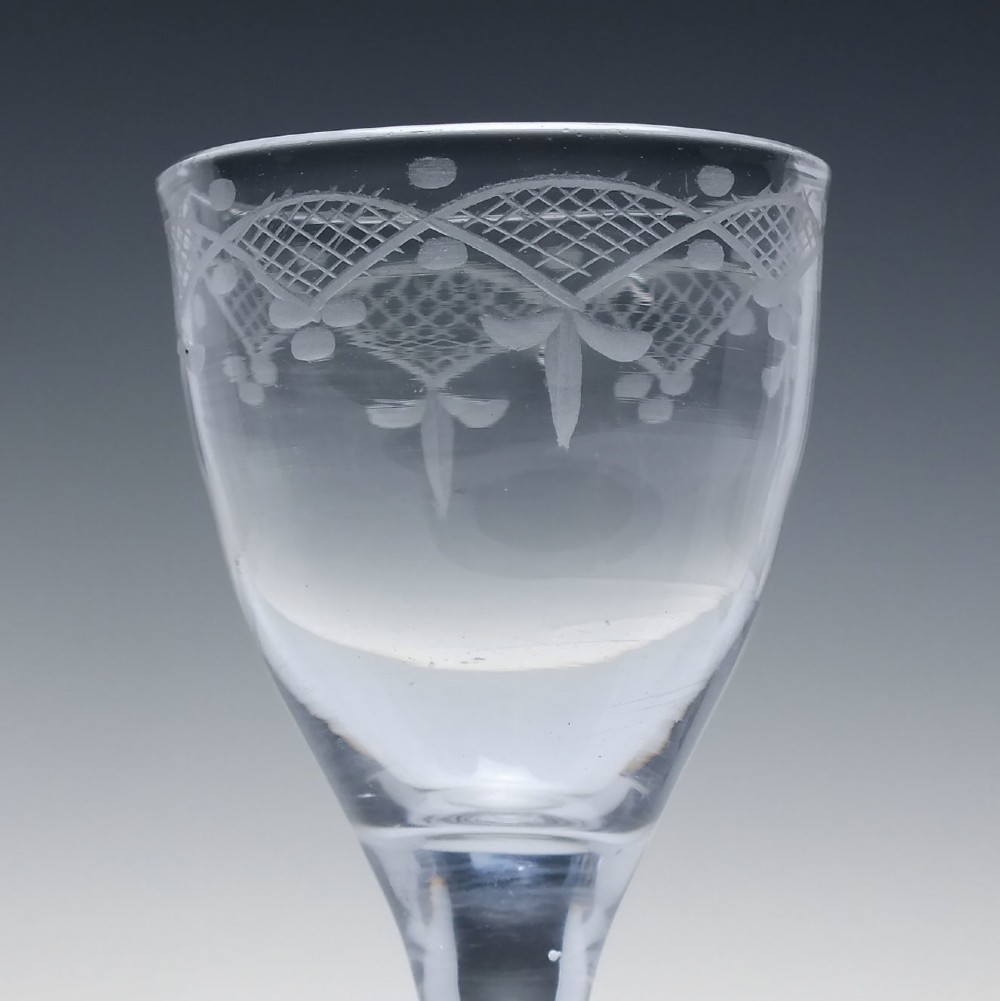 A pair of 18th-century clear glass drams featuring wheel-engraved draped swag borders, plain stems, and wide folded feet. View III