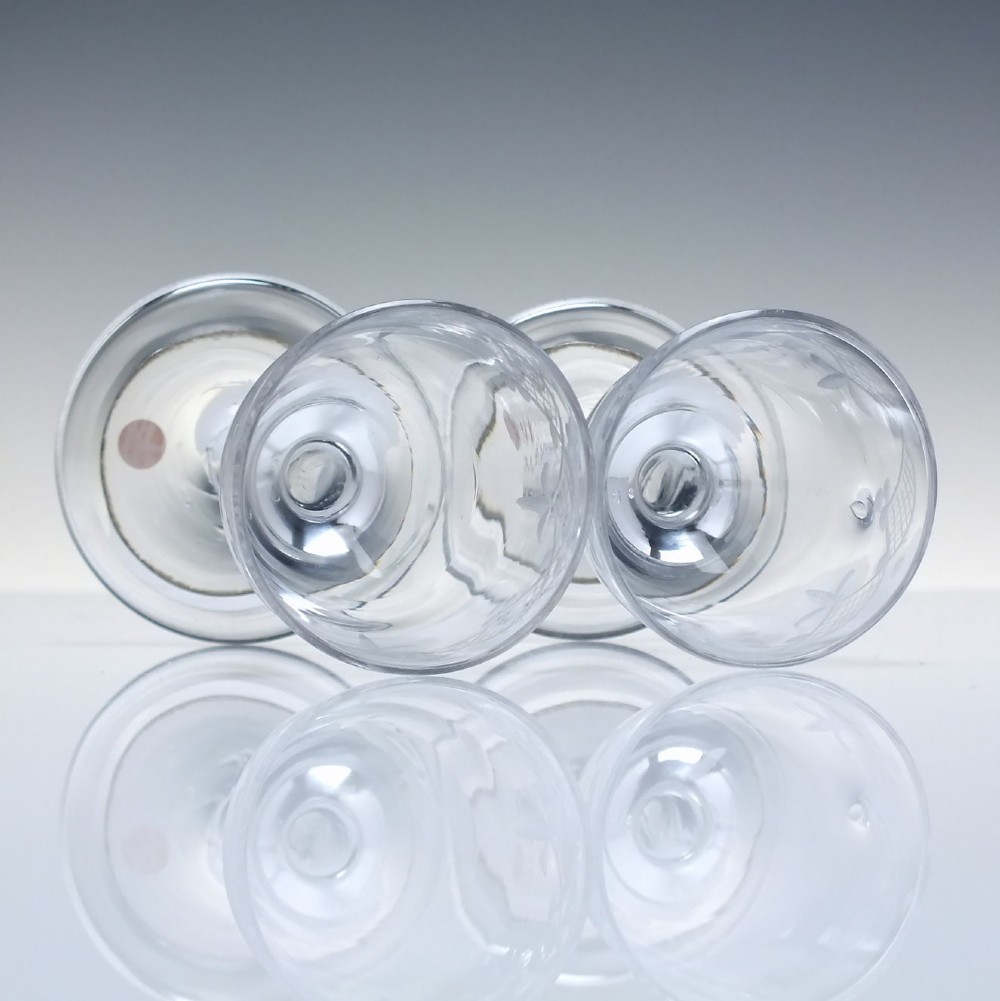 A pair of 18th-century clear glass drams featuring wheel-engraved draped swag borders, plain stems, and wide folded feet. View IV