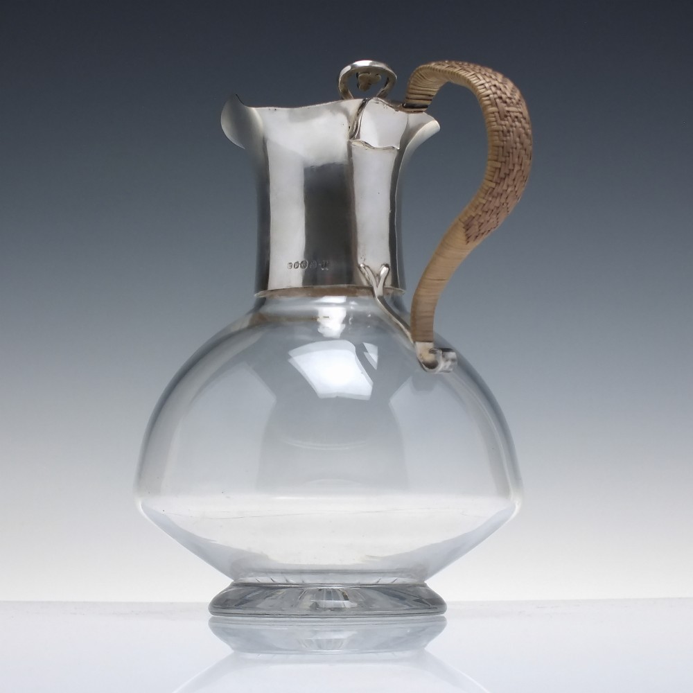 A late Victorian clear glass claret jug featuring a silver-plated neck, hinged lid, spout, and a cane-wrapped curved handle. View II