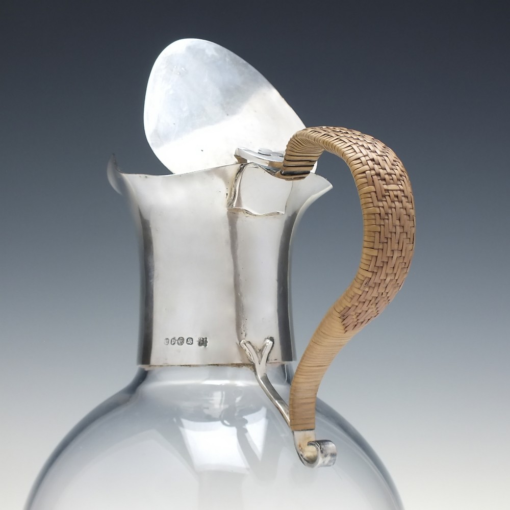 A late Victorian clear glass claret jug featuring a silver-plated neck, hinged lid, spout, and a cane-wrapped curved handle. View IV