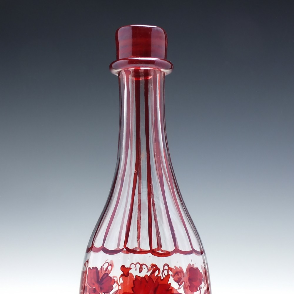 A tall clear glass decanter featuring red hand-painted floral motifs, vertical stripes, and a faceted glass stopper. View V