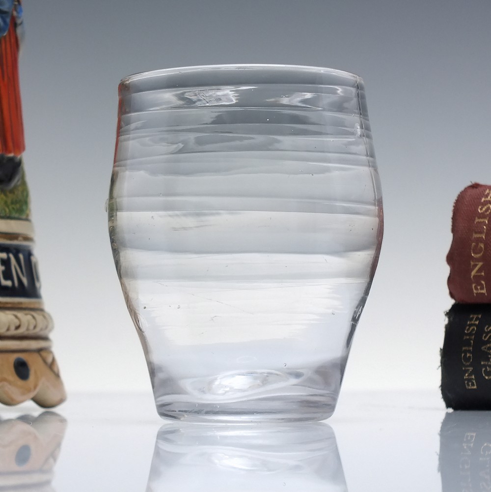 An 18th-century clear lead glass barrel-shaped dram tumbler featuring horizontal moulded rings around the exterior.