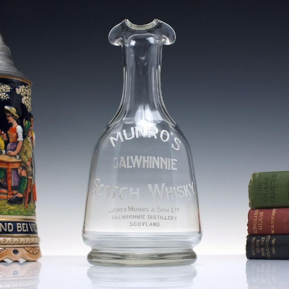 A clear glass antique whisky water carafe featuring white enamelled lettering for Dalwhinnie Scotch Whisky and a pinched pour spout. View II
