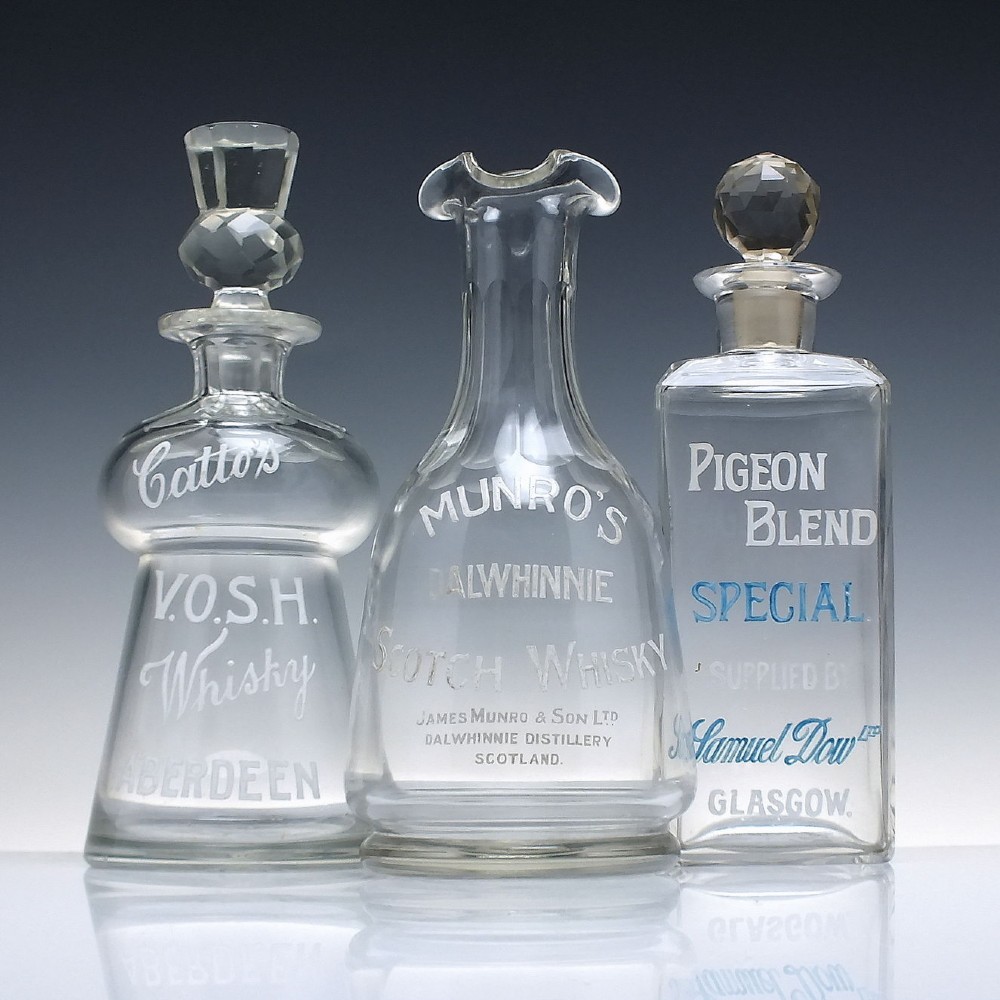 A clear glass antique whisky water carafe featuring white enamelled lettering for Dalwhinnie Scotch Whisky and a pinched pour spout. View III