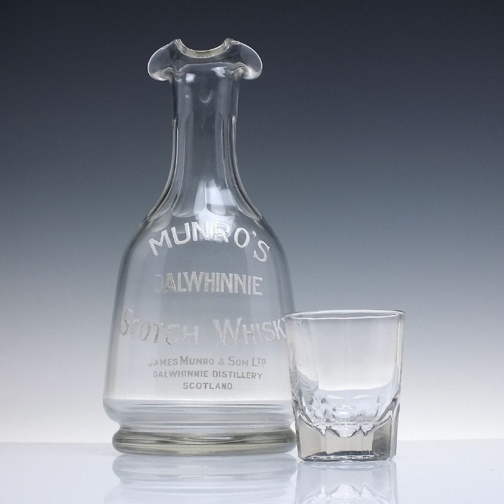 A clear glass antique whisky water carafe featuring white enamelled lettering for Dalwhinnie Scotch Whisky and a pinched pour spout. View IV