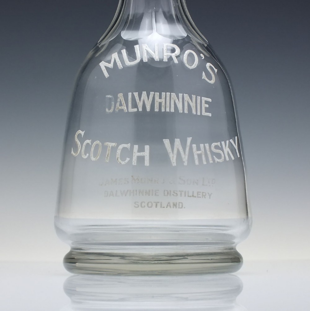 A clear glass antique whisky water carafe featuring white enamelled lettering for Dalwhinnie Scotch Whisky and a pinched pour spout. View VII