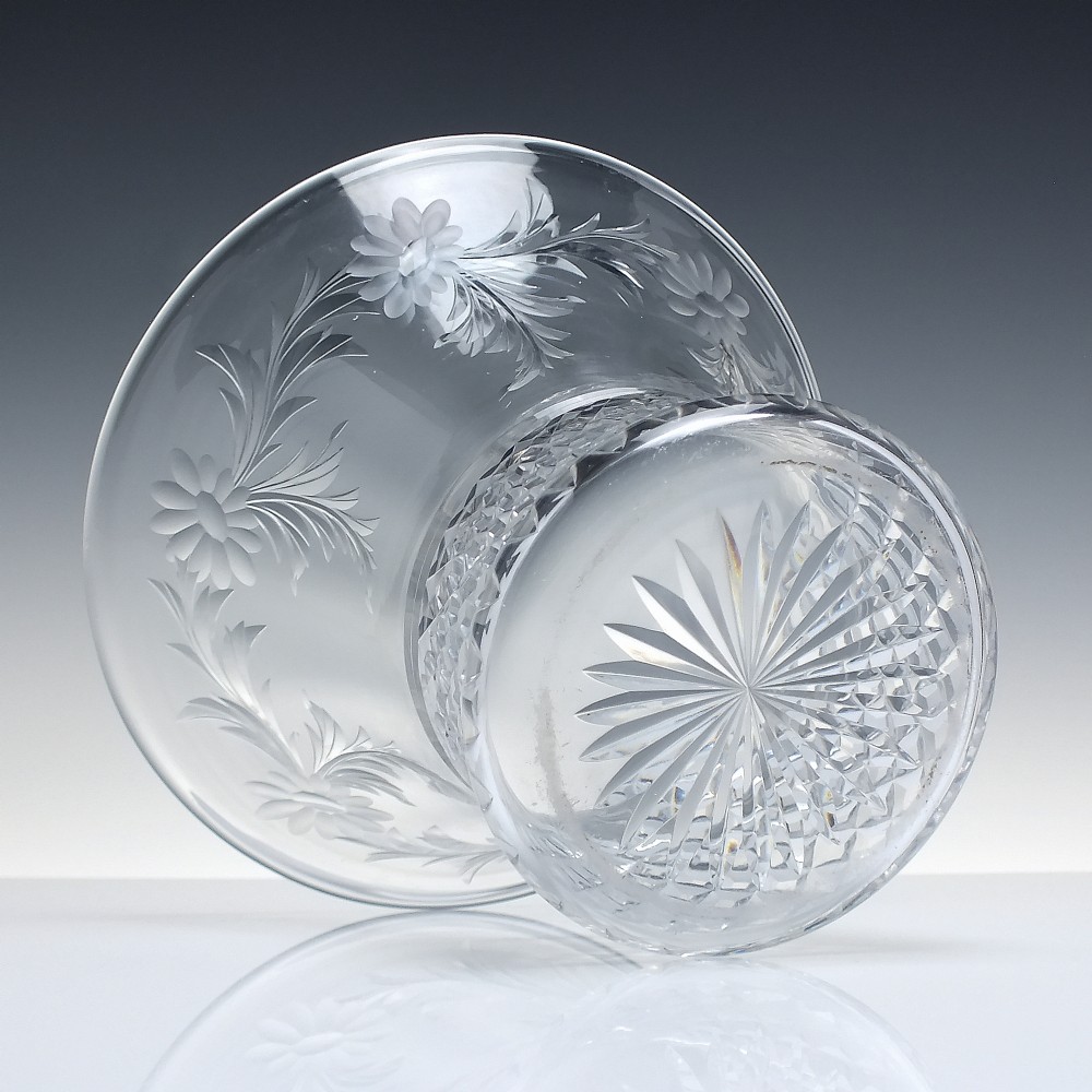 A clear cut crystal vase featuring a flared upper rim with engraved floral details above a geometric diamond-cut lower body. View III