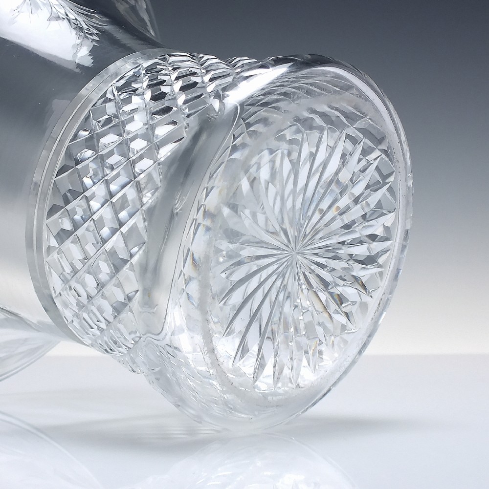 A clear cut crystal vase featuring a flared upper rim with engraved floral details above a geometric diamond-cut lower body. View IV