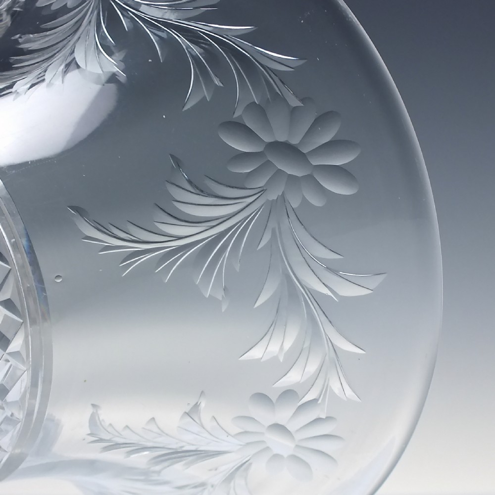 A clear cut crystal vase featuring a flared upper rim with engraved floral details above a geometric diamond-cut lower body. View V