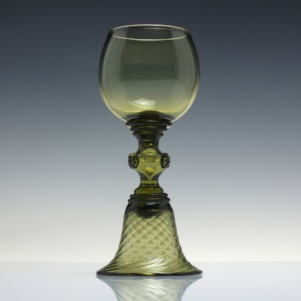 An olive green glass roemer goblet featuring a bulbous bowl, a central stem adorned with applied prunts, and a flared ribbed pedestal base.