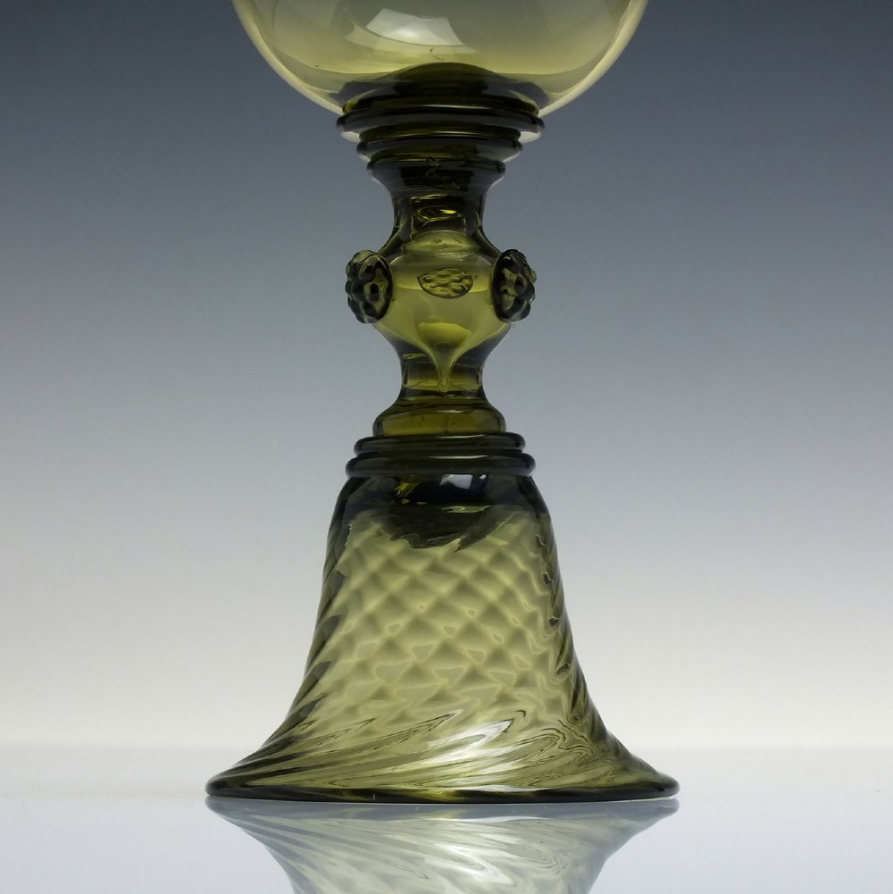 An olive green glass roemer goblet featuring a bulbous bowl, a central stem adorned with applied prunts, and a flared ribbed pedestal base. View IV