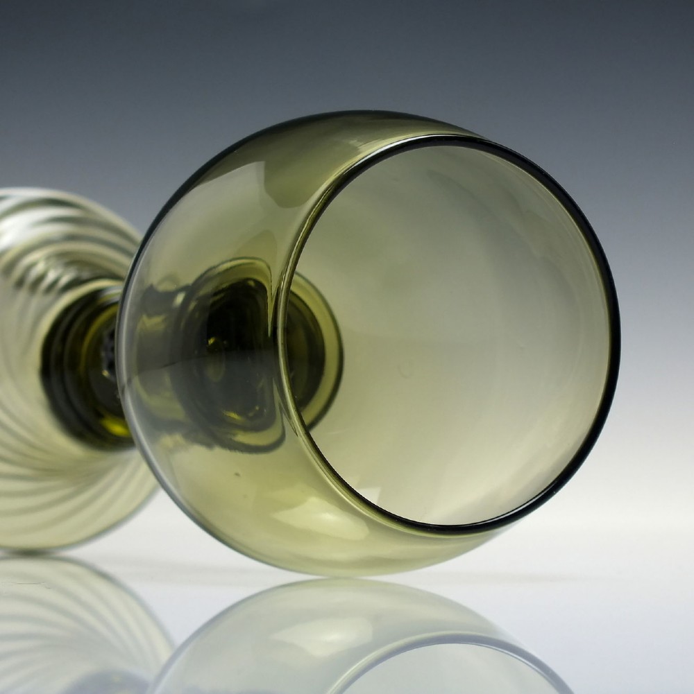 An olive green glass roemer goblet featuring a bulbous bowl, a central stem adorned with applied prunts, and a flared ribbed pedestal base. View VI