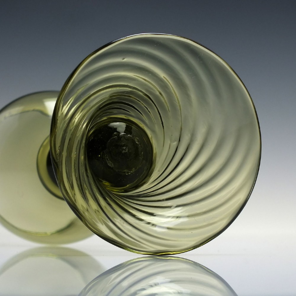 An olive green glass roemer goblet featuring a bulbous bowl, a central stem adorned with applied prunts, and a flared ribbed pedestal base. View VII