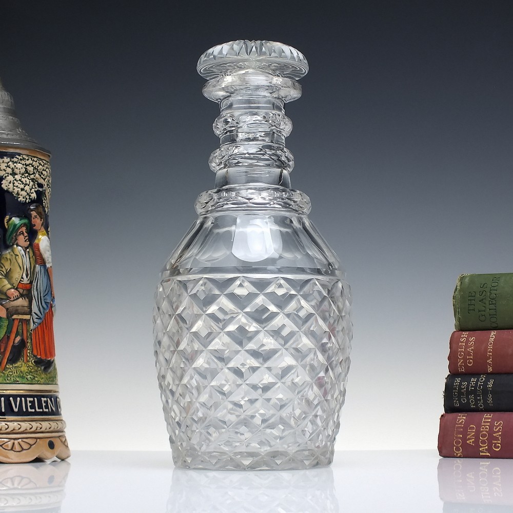 A clear Victorian cut glass wine decanter featuring a diamond-patterned lower body, ringed neck, and a matching faceted stopper.