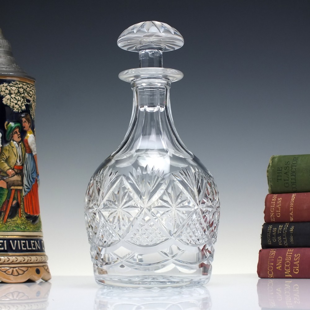 A clear cut lead crystal spirit decanter with starburst patterning and a fitted flat-topped glass stopper.