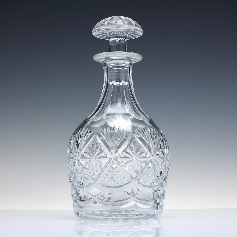A clear cut lead crystal spirit decanter with starburst patterning and a fitted flat-topped glass stopper. View II