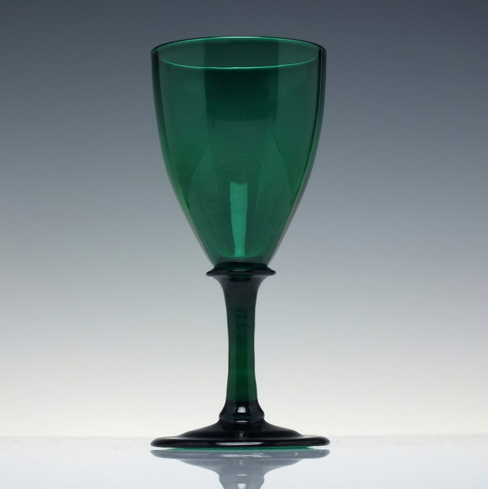 A mid-nineteenth-century wine glass made from deep emerald green glass with a slender stem and flat circular foot. View II
