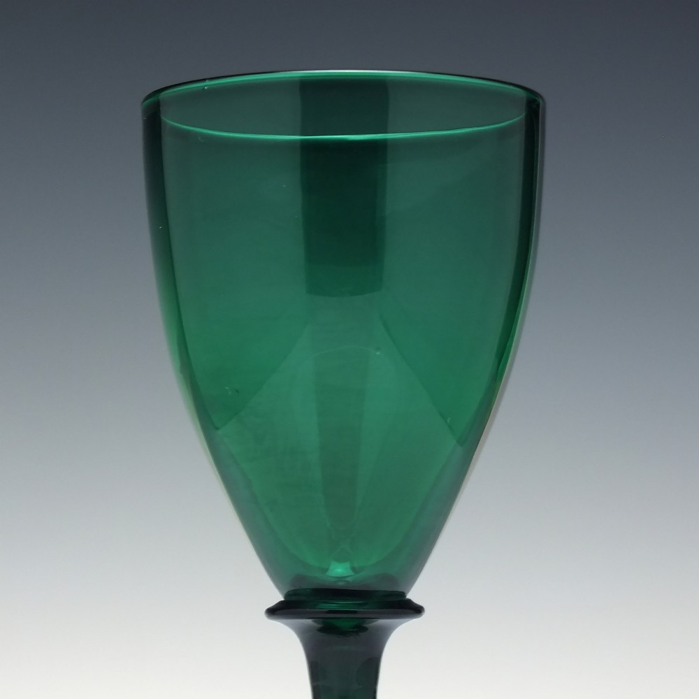 A mid-nineteenth-century wine glass made from deep emerald green glass with a slender stem and flat circular foot. View IV