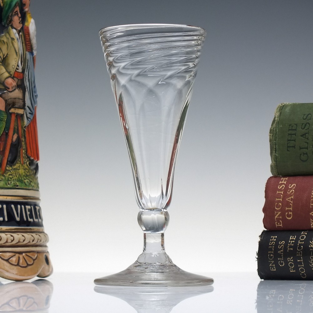 An eighteenth-century clear glass ale goblet featuring spiral wrythen moulding on a conical bowl supported by a knopped stem and circular foot.
