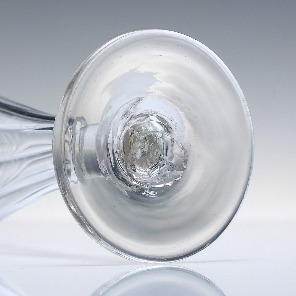 An eighteenth-century clear glass ale goblet featuring spiral wrythen moulding on a conical bowl supported by a knopped stem and circular foot. View V