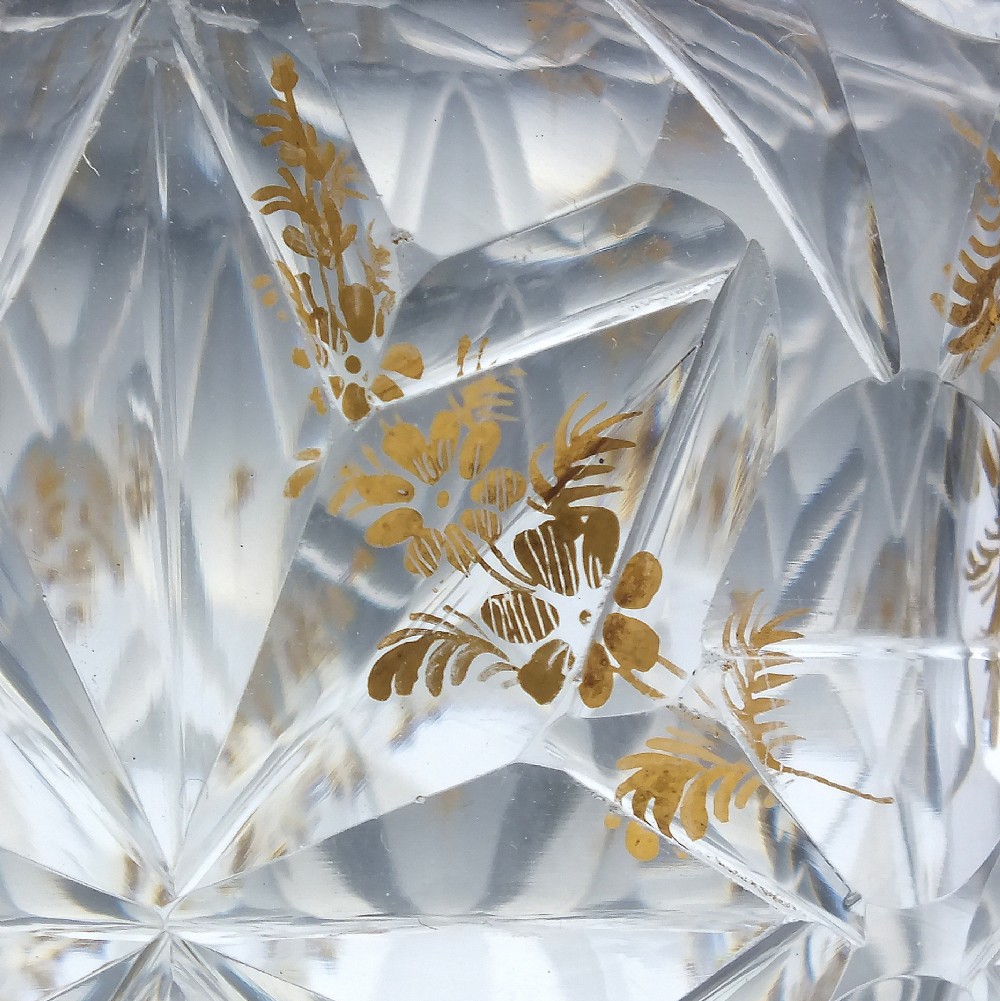 A clear cut glass decanter with gilded lettering on the shoulder, a diamond facetted body, and a facetted glass stopper. View VIII