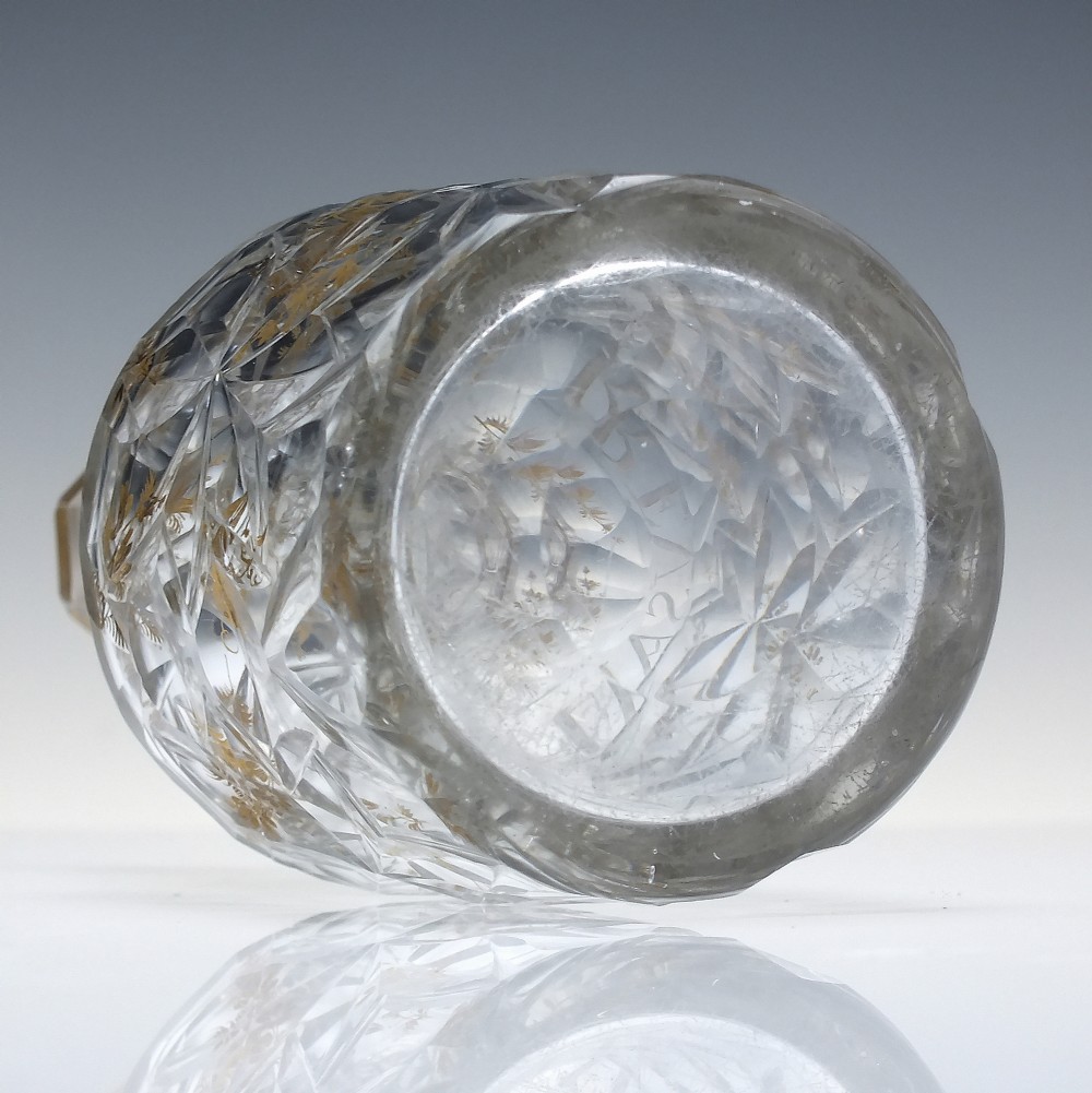 A clear cut glass decanter with gilded lettering on the shoulder, a diamond facetted body, and a facetted glass stopper. View XI