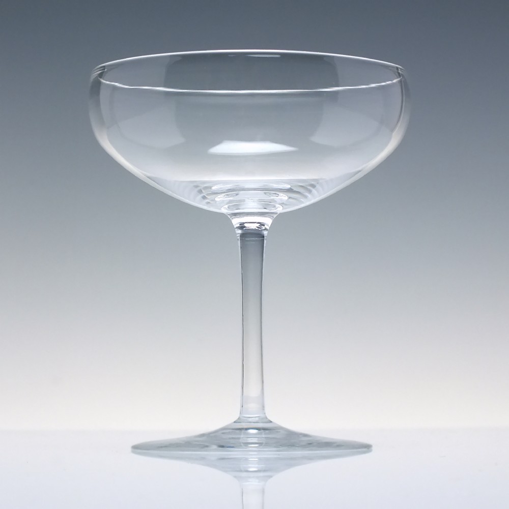 A set of six clear Edwardian crystal champagne coupes with wide saucer bowls and slender stems arranged in a line. View III