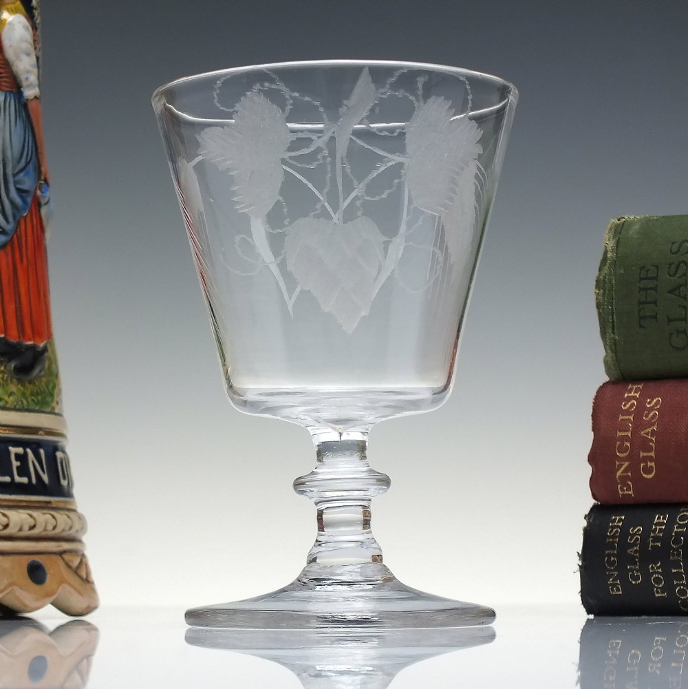 A clear Georgian glass rummer with a cup-shaped bowl wheel-engraved with hop and barley motifs, set on a short knopped stem and flat circular base.