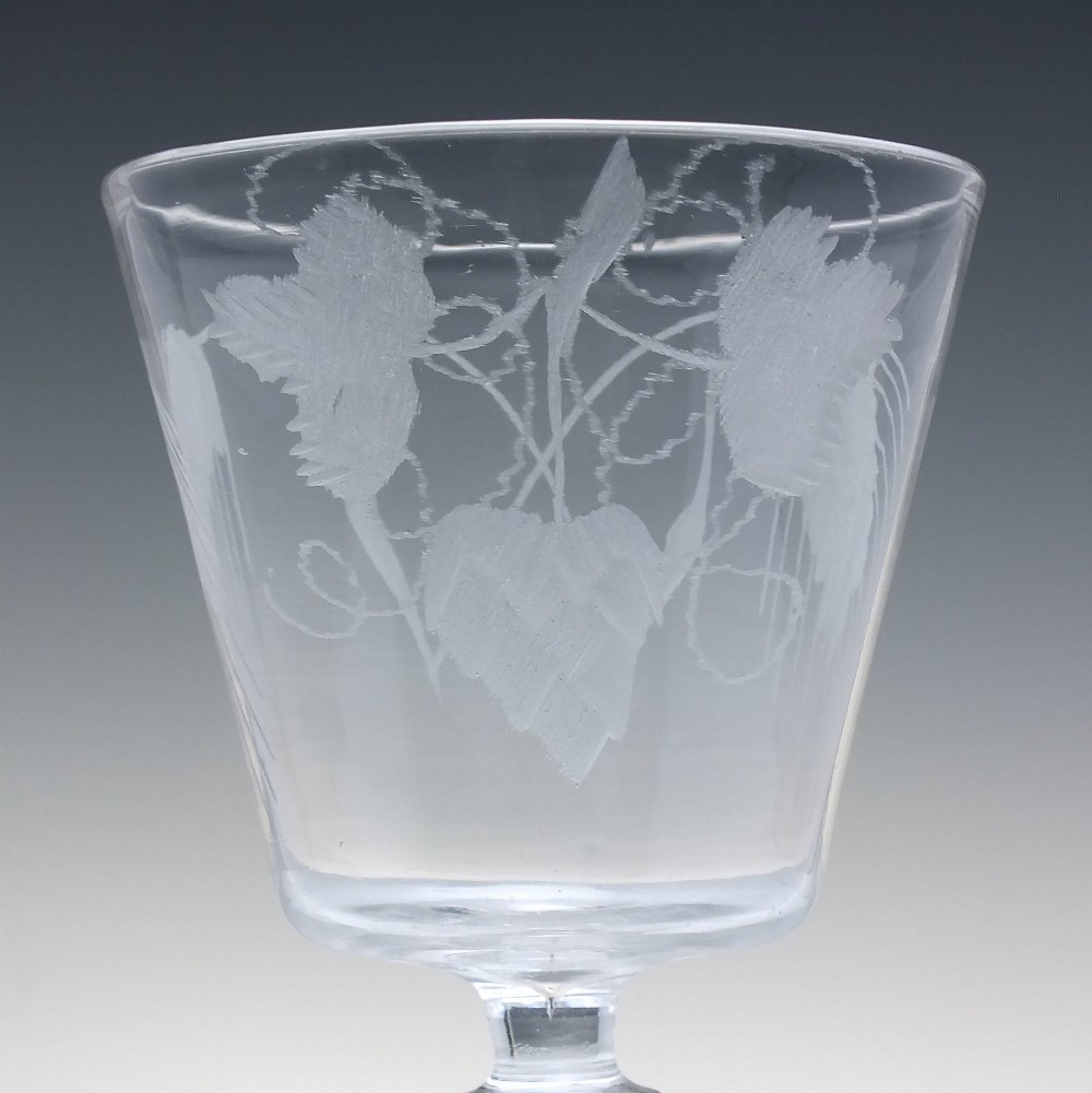 A clear Georgian glass rummer with a cup-shaped bowl wheel-engraved with hop and barley motifs, set on a short knopped stem and flat circular base. View IV