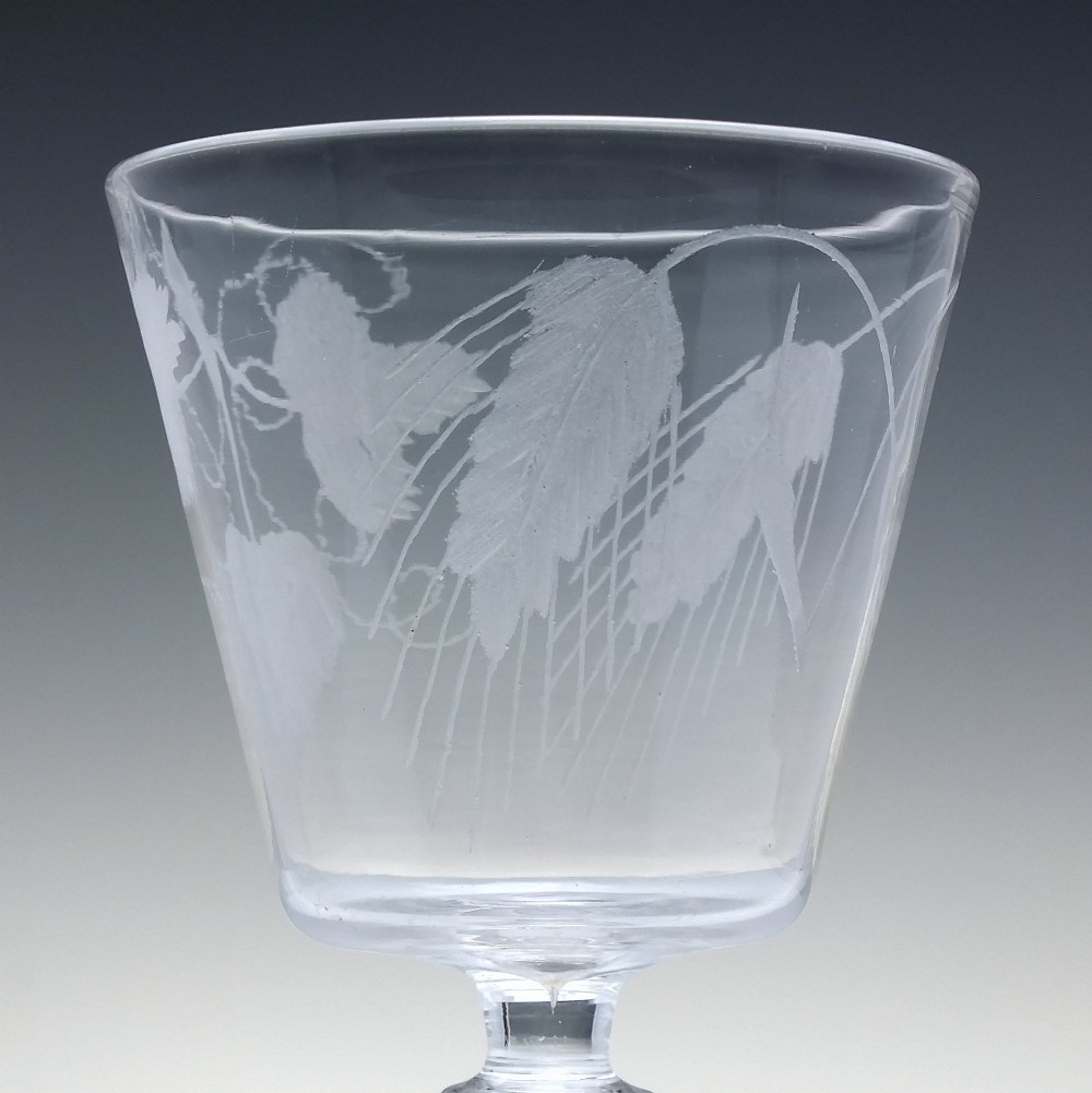 A clear Georgian glass rummer with a cup-shaped bowl wheel-engraved with hop and barley motifs, set on a short knopped stem and flat circular base. View V