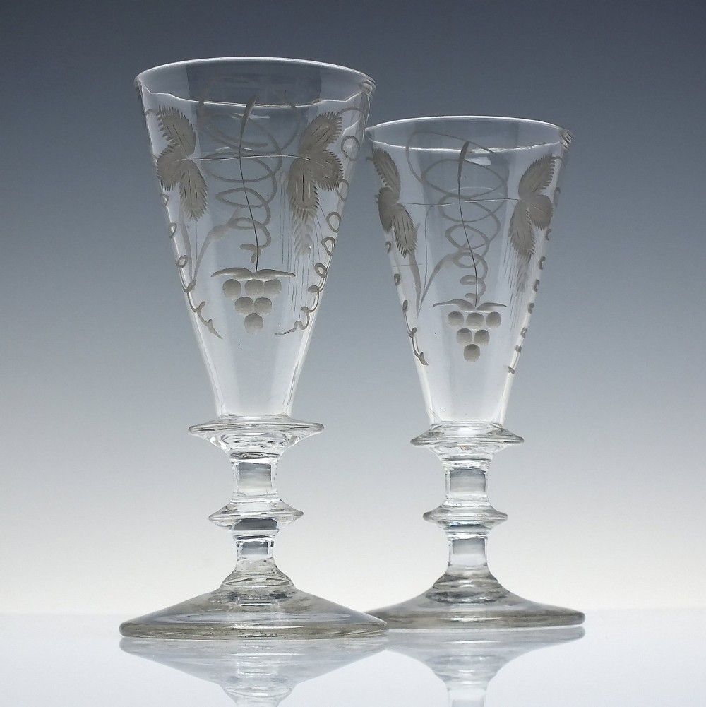 A pair of clear hand-blown Georgian glass goblets featuring wheel-engraved motifs of hops and barley on conical bowls above knopped stems and conical bases. View II