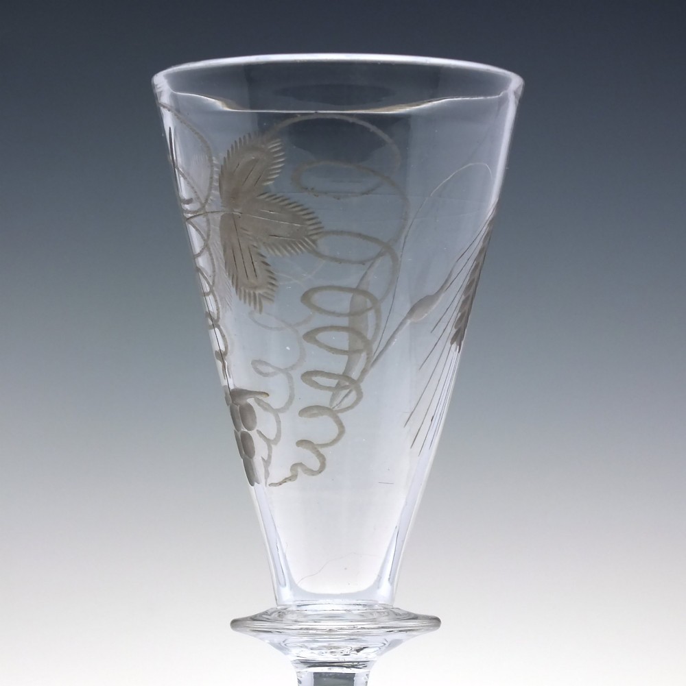 A pair of clear hand-blown Georgian glass goblets featuring wheel-engraved motifs of hops and barley on conical bowls above knopped stems and conical bases. View VI