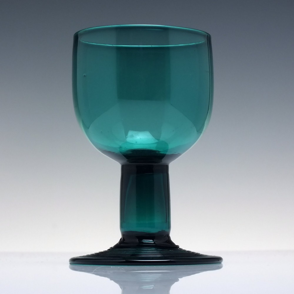 An 18th-century emerald green hand-blown glass wine goblet featuring a rounded cup, thick cylindrical stem, and circular foot. View II