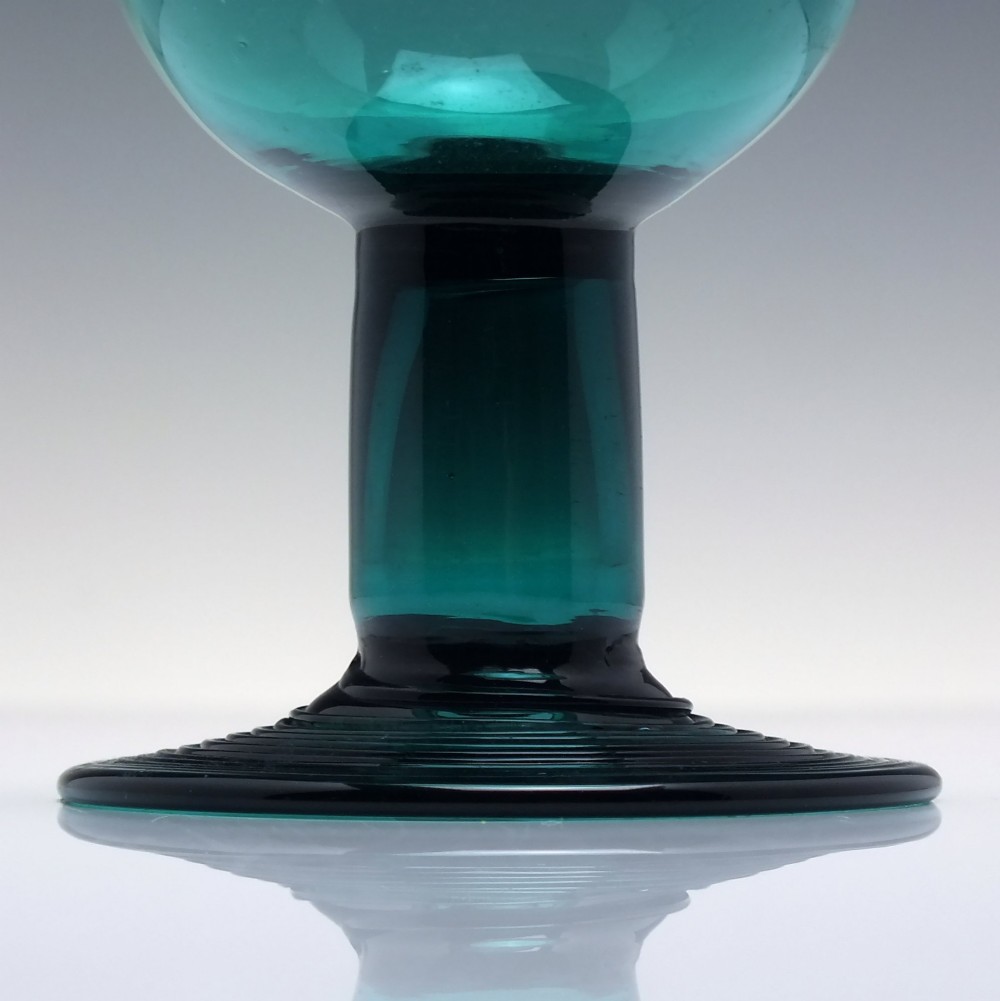 An 18th-century emerald green hand-blown glass wine goblet featuring a rounded cup, thick cylindrical stem, and circular foot. View III