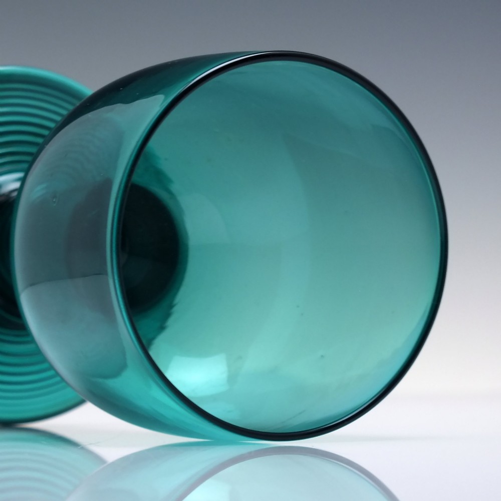 An 18th-century emerald green hand-blown glass wine goblet featuring a rounded cup, thick cylindrical stem, and circular foot. View V