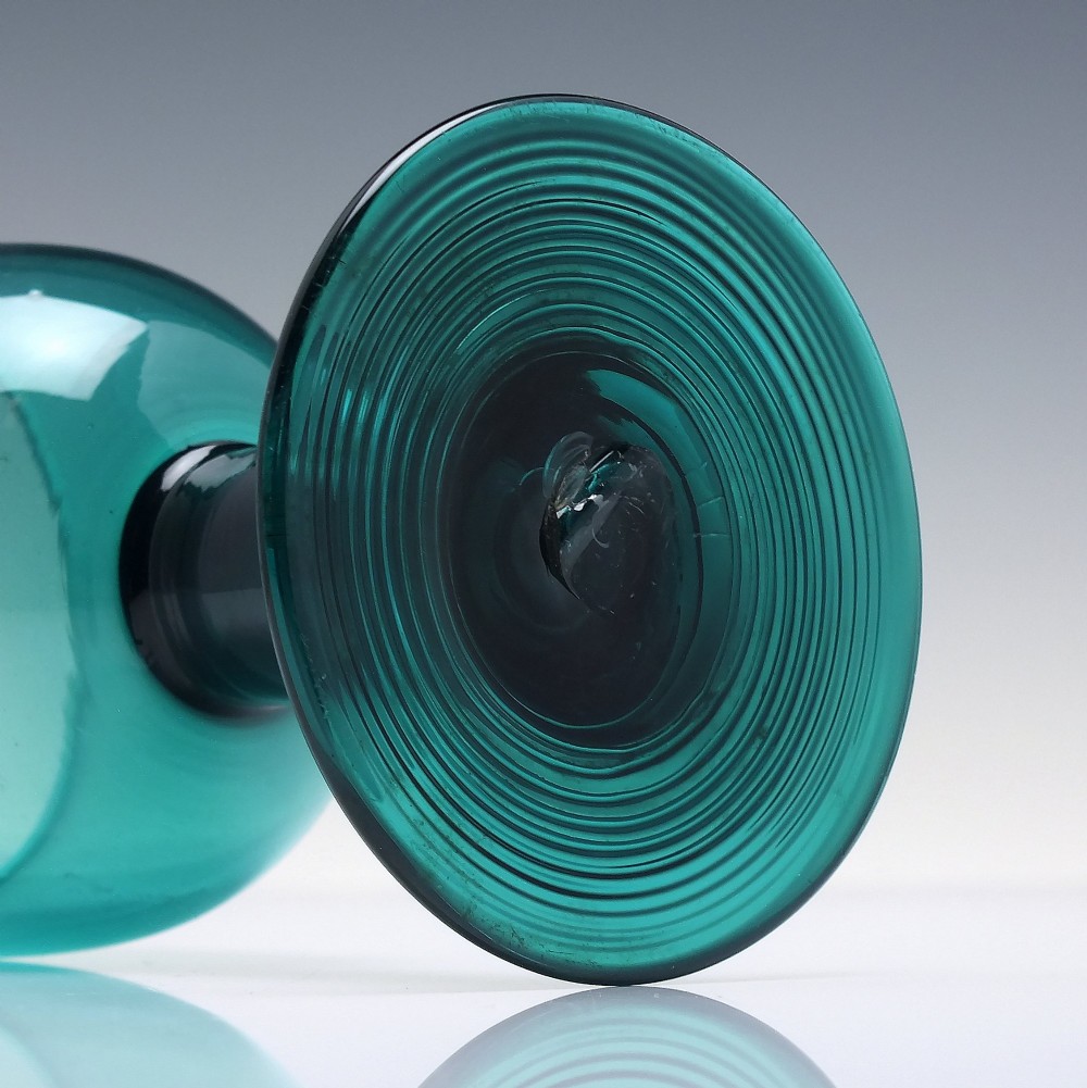 An 18th-century emerald green hand-blown glass wine goblet featuring a rounded cup, thick cylindrical stem, and circular foot. View VI