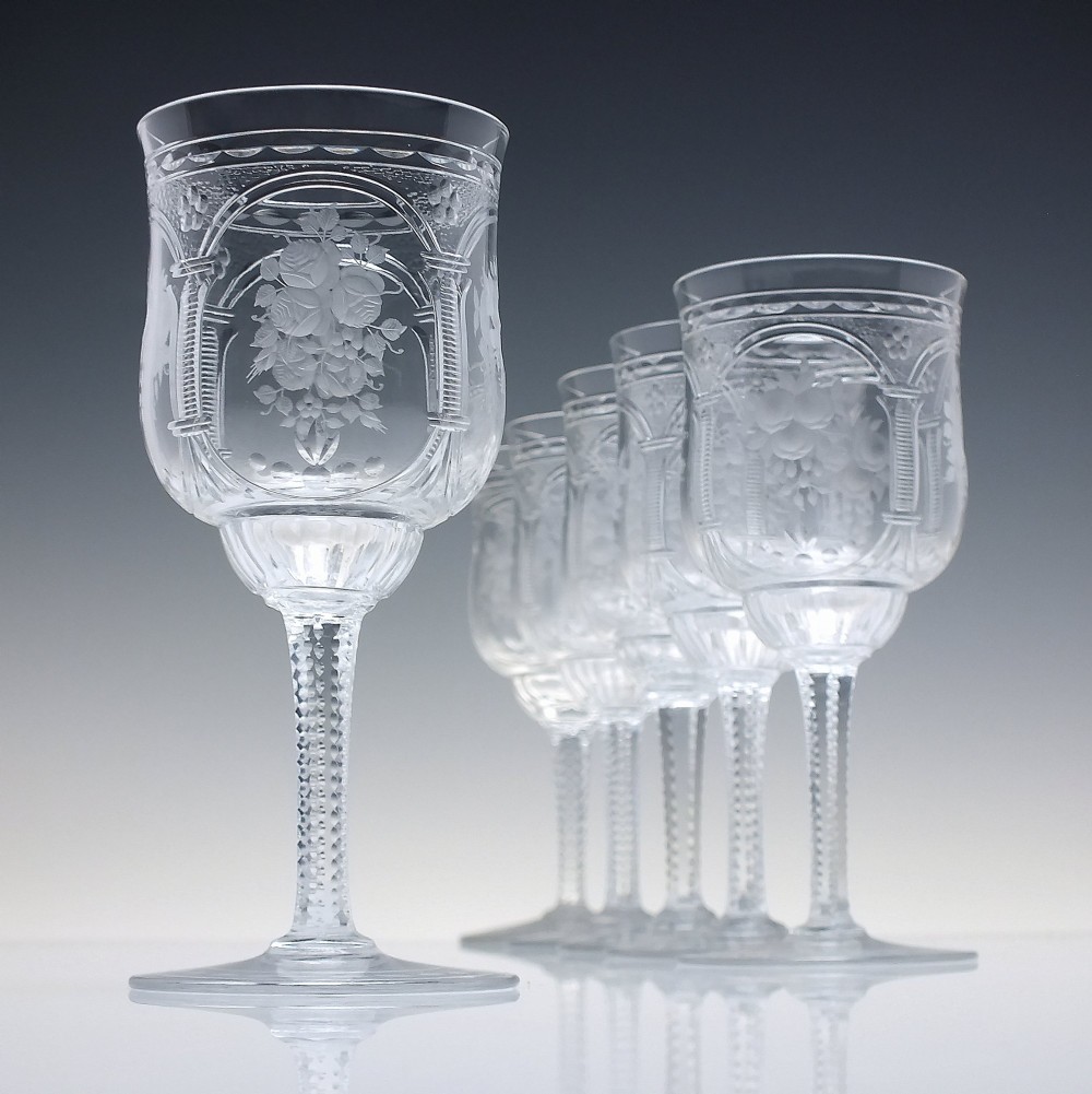 A set of six clear lead crystal wine glasses featuring intricate acid-etched floral panels and textured facet-cut stems.