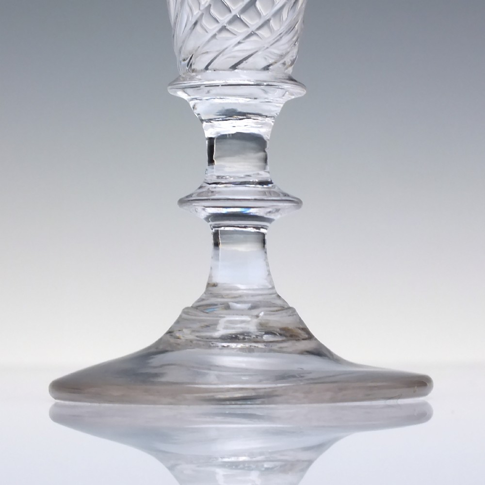 A clear Georgian ale glass featuring half-wrythen spiral moulding on the conical bowl above a knopped stem. View III