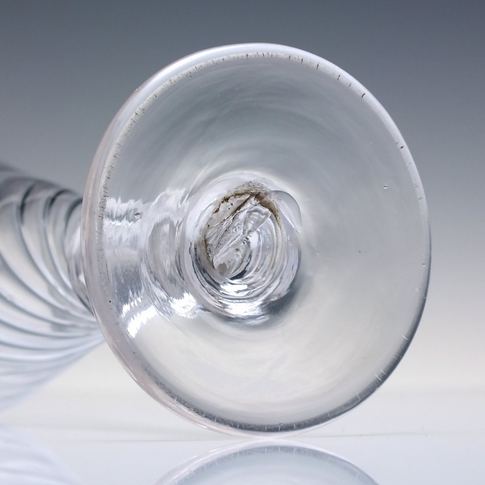 A clear Georgian ale glass featuring half-wrythen spiral moulding on the conical bowl above a knopped stem. View V