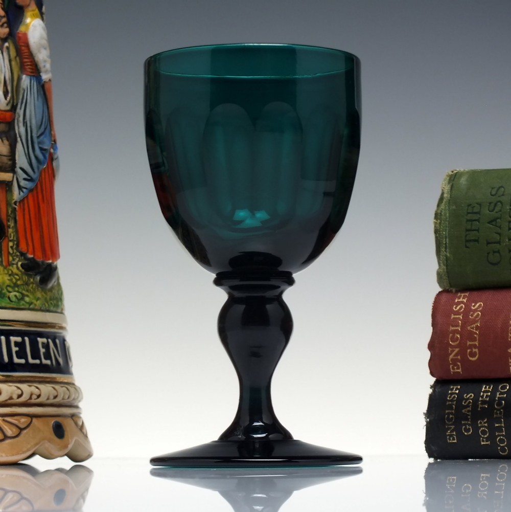 An early 19th-century turquoise green glass wine goblet featuring a cut bowl and a knopped stem on a flat circular base.