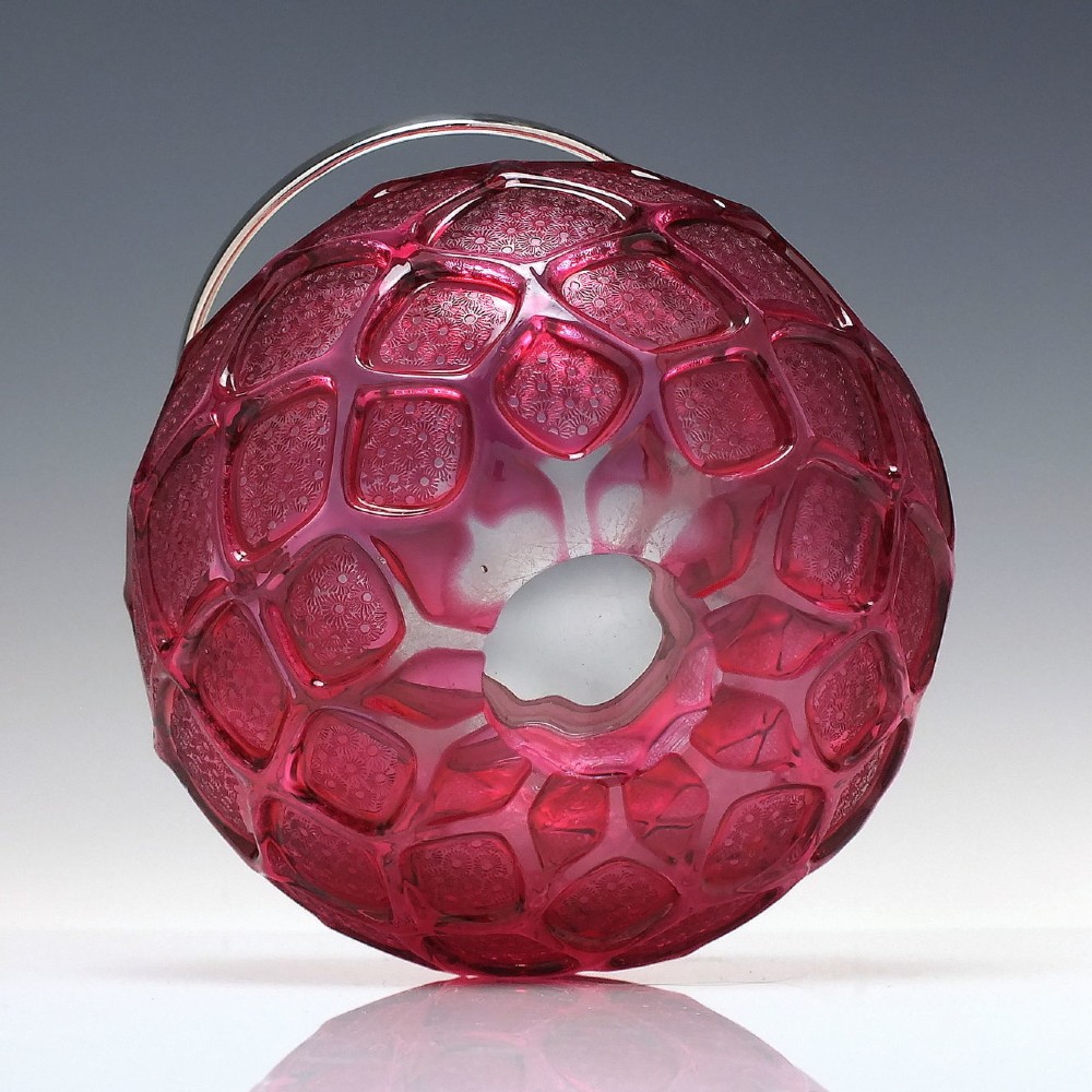 A Victorian cranberry glass biscuit barrel featuring a diamond-quilted pattern with internal floral etching and a silver-plated rim, lid, and overhead swing handle. View V