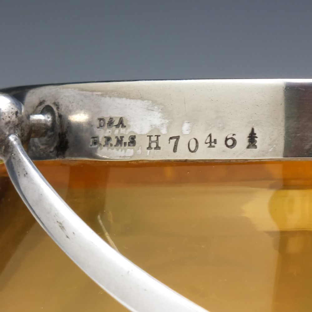 An Art Nouveau amber glass biscuit barrel featuring green peacock eye trailing decoration and a silver-plated metal rim, lid, and swing handle. View VI