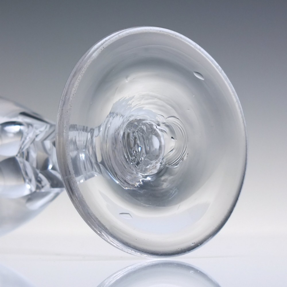 An 18th-century clear lead crystal dram glass with a rounded bowl and a diamond facet-cut stem resting on a circular base. View VI