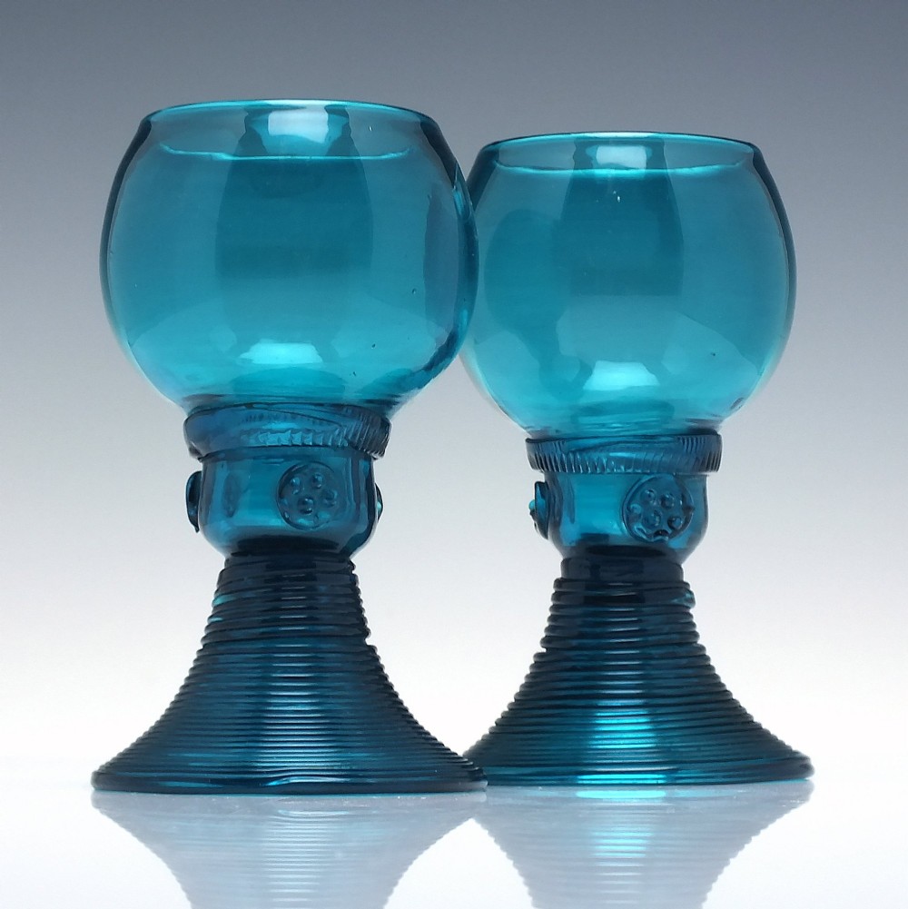 A pair of early 19th-century peacock blue glass roemers with globular bowls, prunted stems, and broad coiled pedestals.