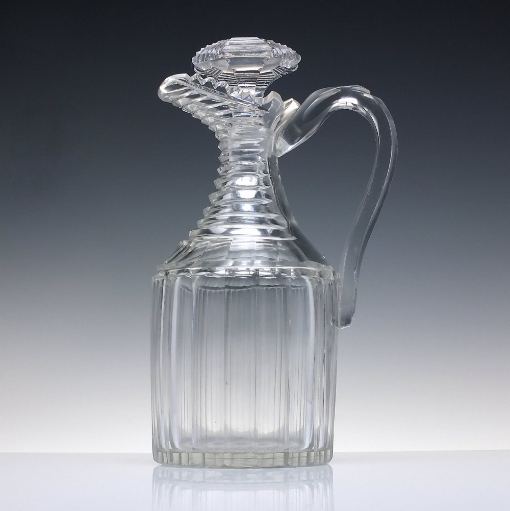 A clear Georgian Regency cut glass claret jug with a step-cut neck, panelled body, applied handle, and faceted stopper. View II