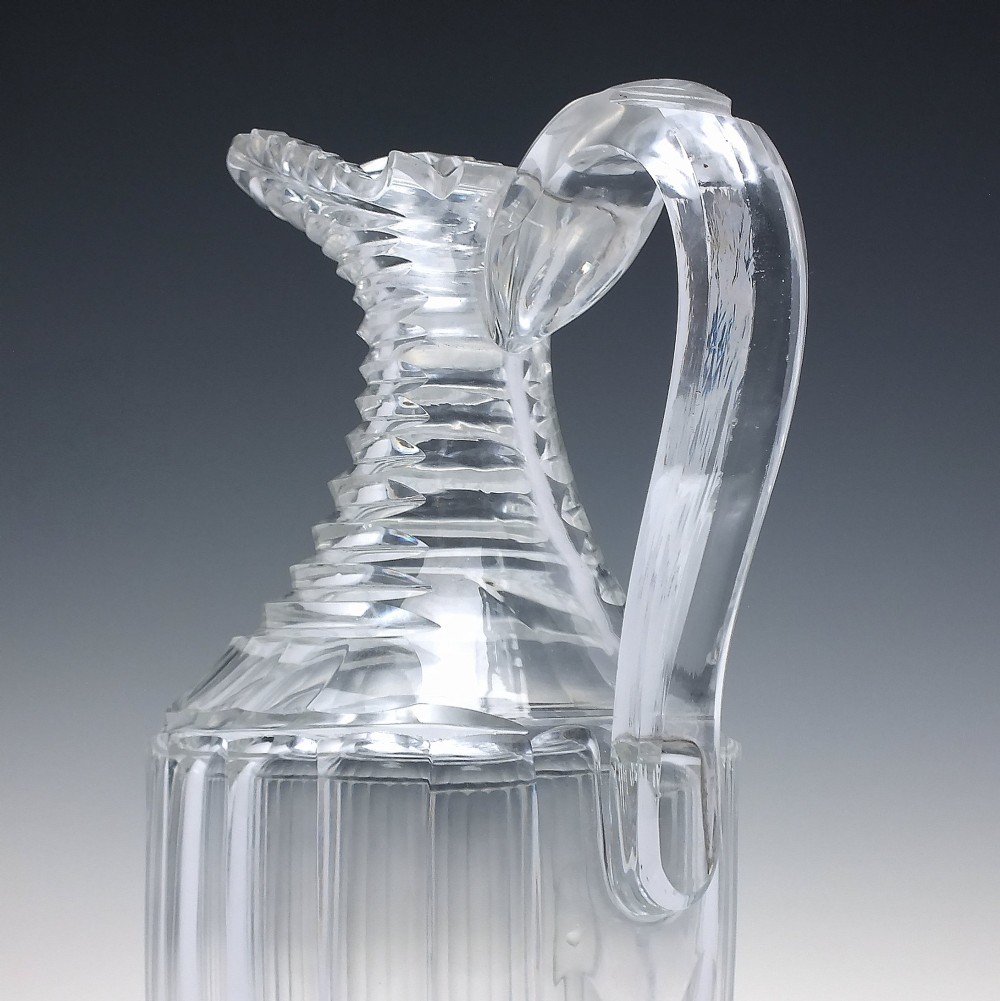 A clear Georgian Regency cut glass claret jug with a step-cut neck, panelled body, applied handle, and faceted stopper. View III